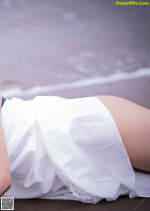 A woman in a white tank top and panties smoking a cigarette.