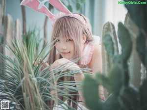 A woman in a pink bunny costume sitting on a bed of white rocks.