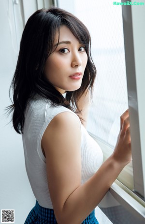 A naked asian woman leaning against a wall.
