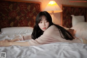 A woman sitting on a bed with her legs crossed.