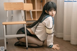 A woman in a school uniform sitting on a desk.