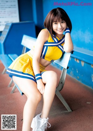 A woman in a yellow and blue cheerleading uniform posing for a magazine.