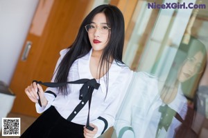 A woman in a white shirt and black skirt sitting on a table.