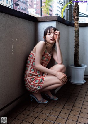 A woman in a black bikini sitting on a window sill.