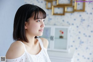 A woman in a white dress sitting on top of a white cabinet.