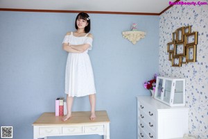 A woman sitting on top of a white dresser.