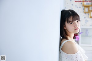 A woman in a white dress sitting on top of a dresser.