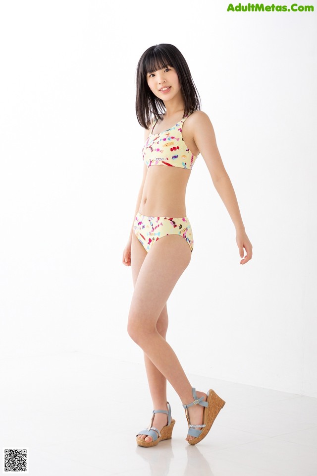 A woman in a bikini standing on a white floor.