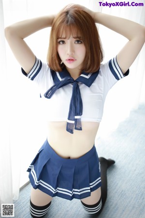 A woman in a sailor outfit holding a lollipop.