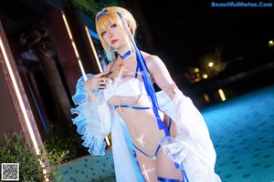 A woman in a white and blue lingerie posing by a pool.