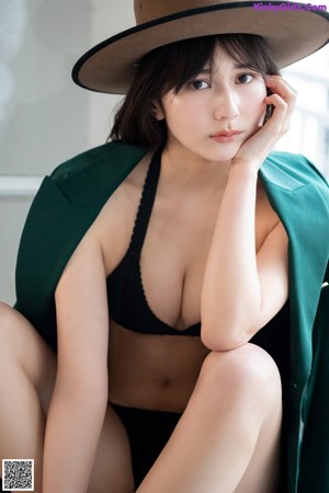 A woman in a black bikini and a green coat.