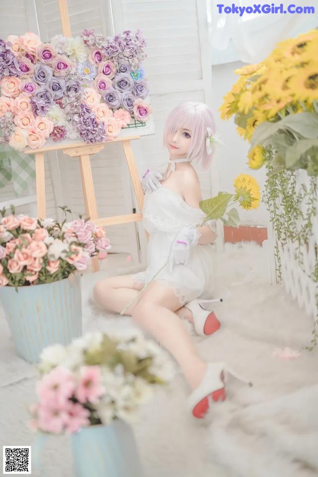 A woman sitting on the floor next to a bunch of flowers.