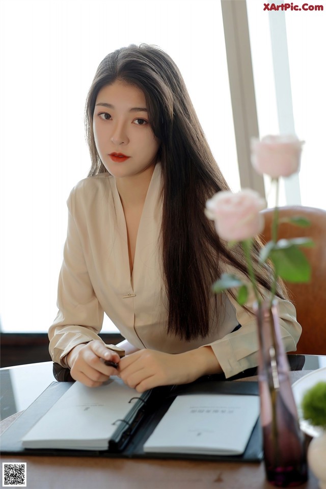 A woman sitting at a table writing in a notebook.