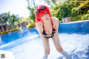 A woman in a bikini sitting on a ladder by a pool.
