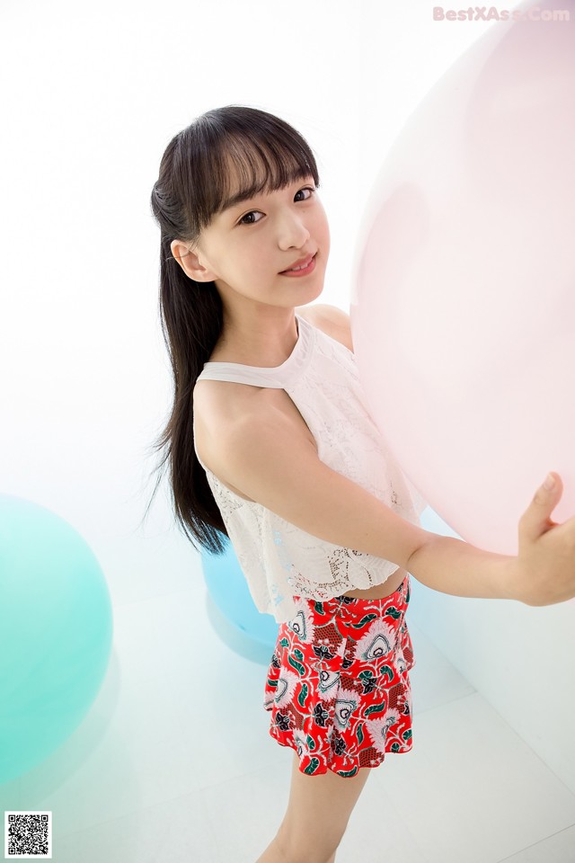 A young girl holding a large pink balloon in her hand.