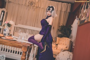 A woman in a purple dress sitting on a chair holding a glass of wine.