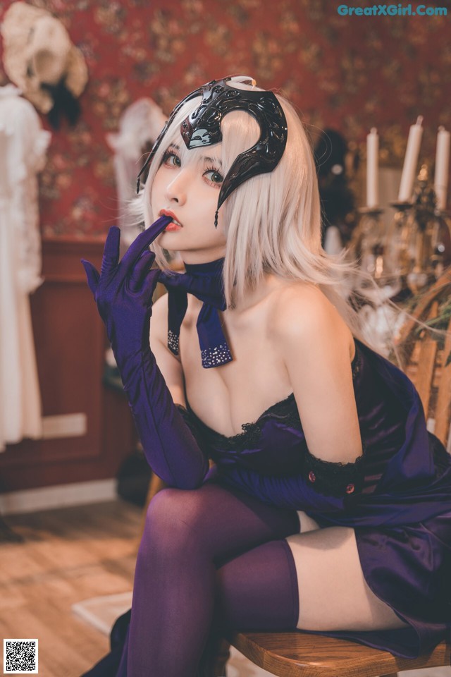 A woman in a purple dress sitting on a wooden chair.