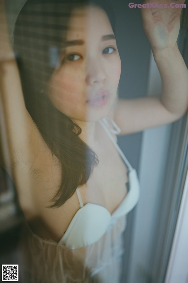 A woman in a white lingerie leaning against a window.