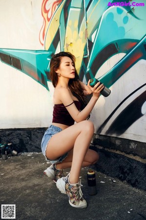 A woman standing in front of a graffiti covered wall.