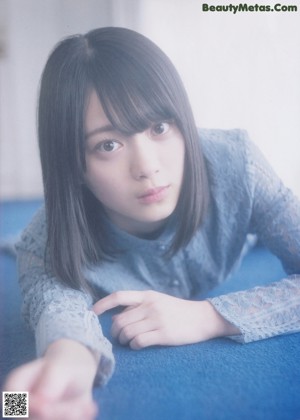 A woman in a blue and white striped shirt is posing for a magazine.