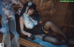 A woman in lingerie sitting on a bed holding a knife.