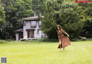 A woman in a brown dress crouching down in a garden.