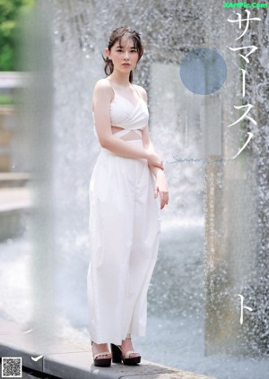 A woman in a gray dress posing by a window.