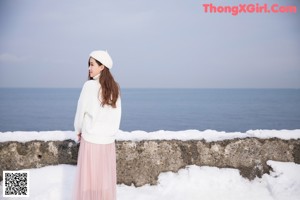 A woman sitting in the snow holding an umbrella.