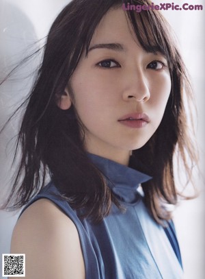 A woman in a blue top and black skirt standing on a bridge.