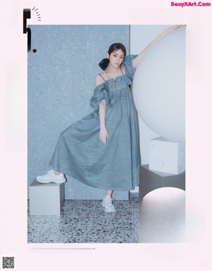 A woman in a gray coat and white pleated skirt posing for a magazine.