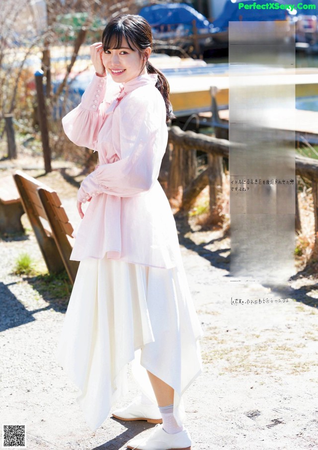 A woman in a pink shirt and white skirt posing for a magazine.