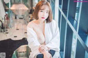 A woman in a black lingerie sitting on a bed.