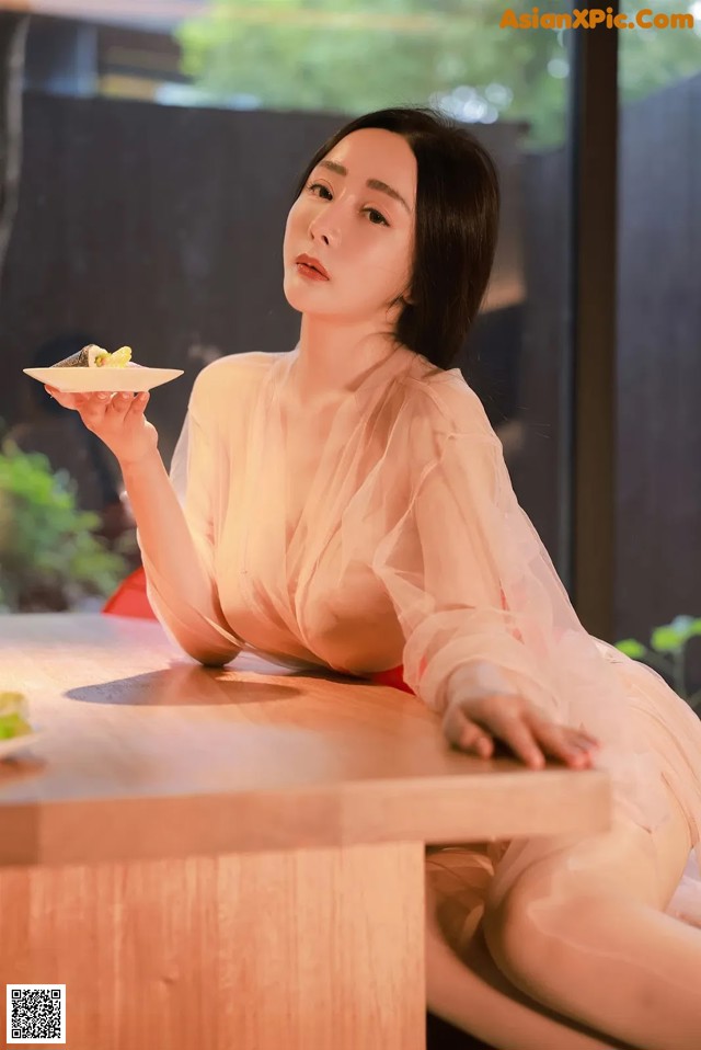 A woman sitting at a table holding a plate of food.