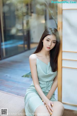 A woman sitting on a couch next to a table.