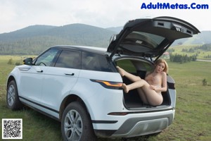 A woman sitting in the driver's seat of a white car.