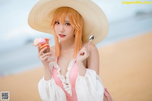 A woman in a pink bikini and a white hat on a beach.