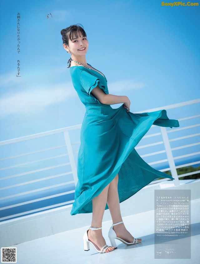 A woman in a blue dress standing on a balcony.