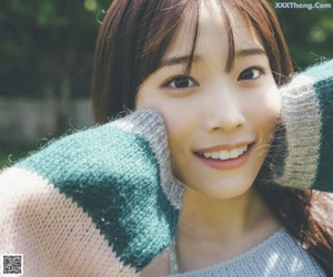 A woman in a striped sweater is standing in the grass.