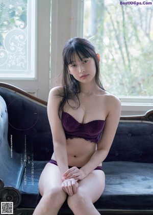 A woman laying on top of a black couch.