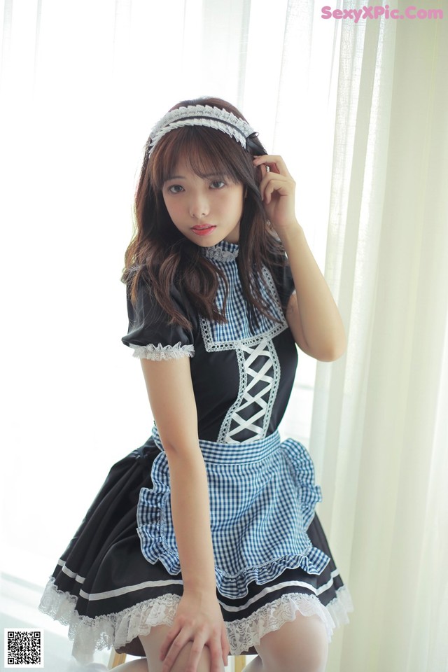 A woman in a blue and white dress sitting on a chair.