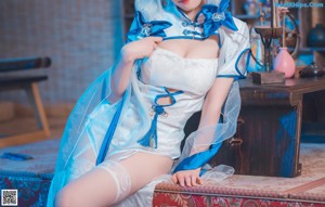 A woman in a blue dress and white stockings sitting on a chair.