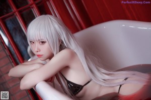 A woman in a bathtub holding a glass of water.