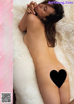 A naked woman sitting on top of a white couch.