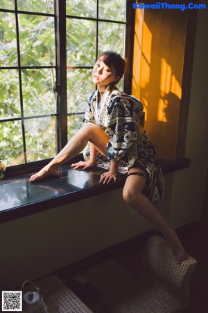 A woman in a kimono sitting on a window sill.
