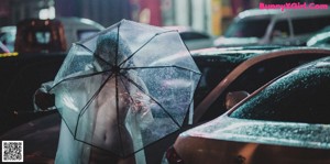 A naked woman wearing a gas mask standing in the rain.